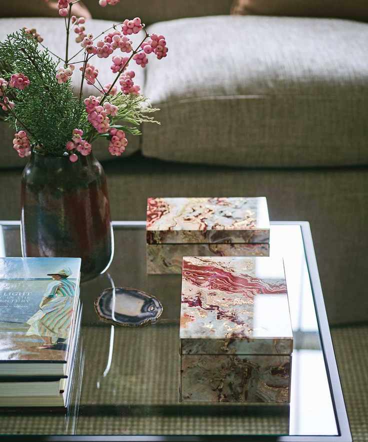 glass coffee table with pink berries in vase
