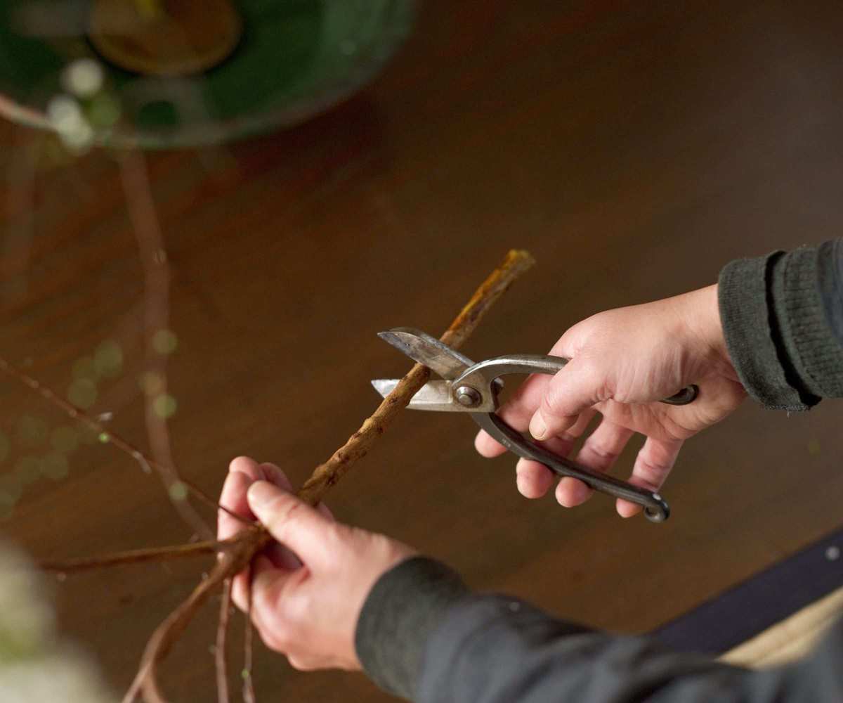 Someone cutting a branch for an Ikeaba flower arrangement