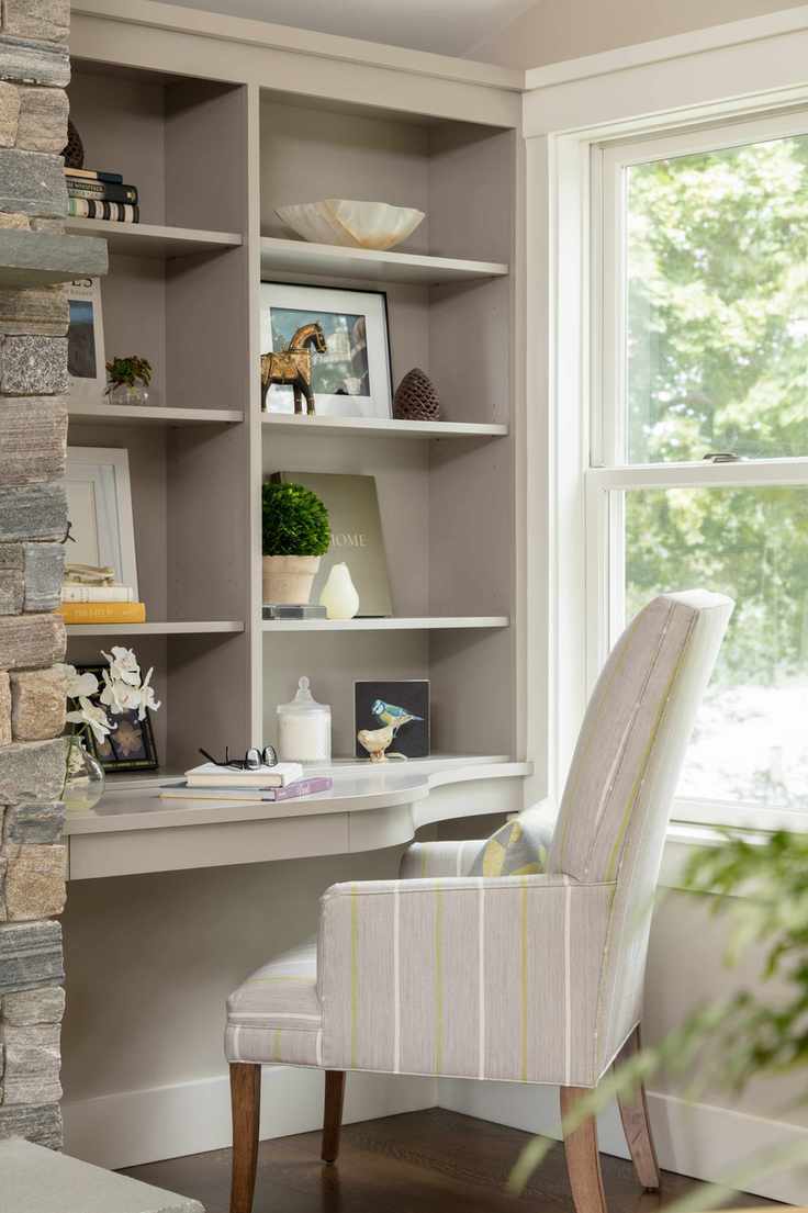 built in home office desk with upholstered chair beside window