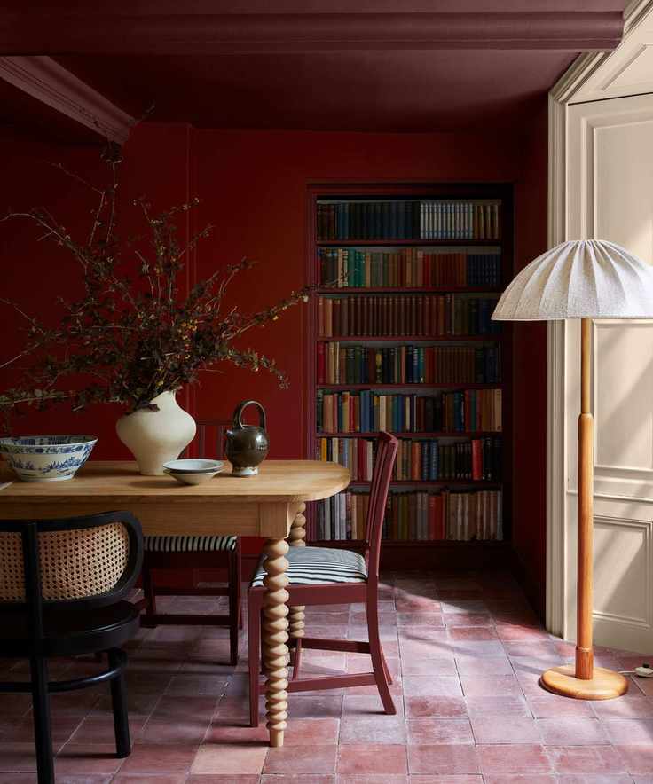 burgundy dining room with terracotta tiles and a painted ceiling and recessed bookshelf nook