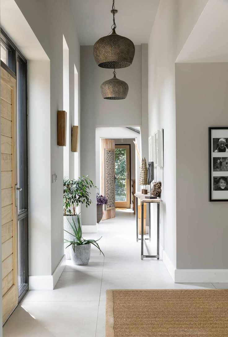 entry way with wooden front door gray green neutral colors and brass pendant lights