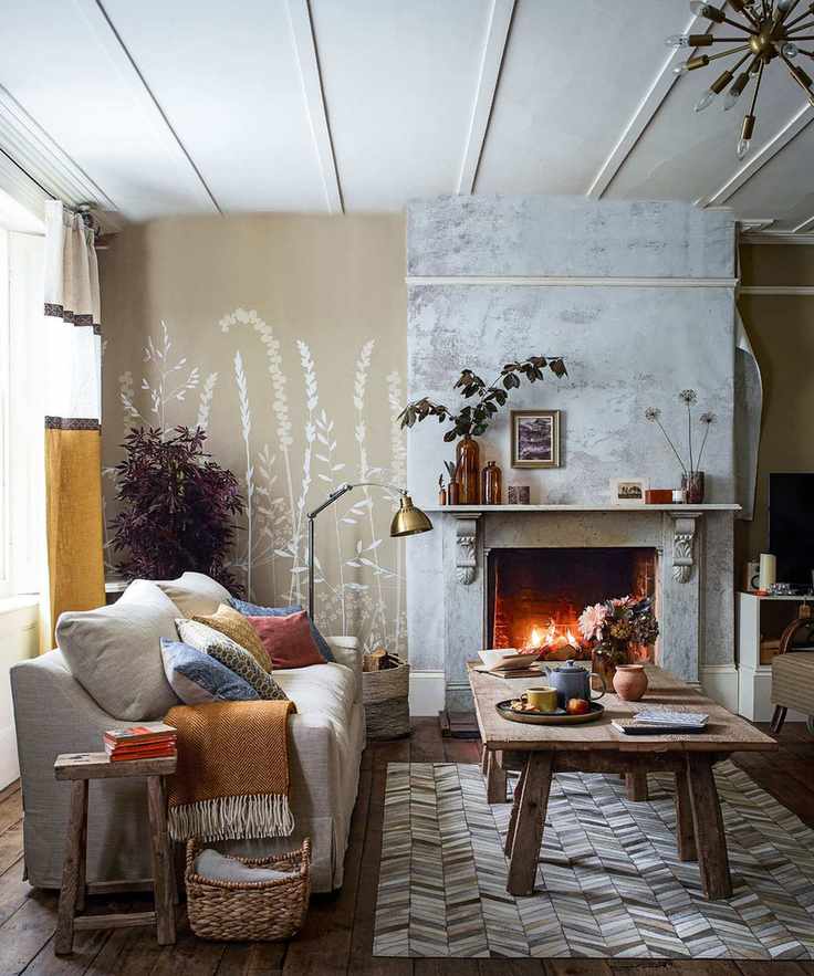 A modern living room featuring a cozy sofa with colorful cushions beside a lit fire.