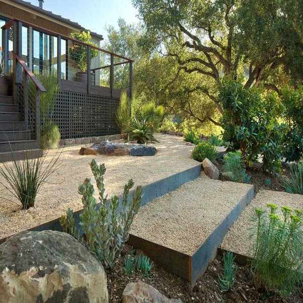 Gravelled steps in a sloped front yard with green trees and bushes.