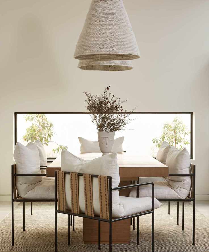 Neutral dining room with two low hanging pendants, dining chairs, wooden dining table, low rectangular window