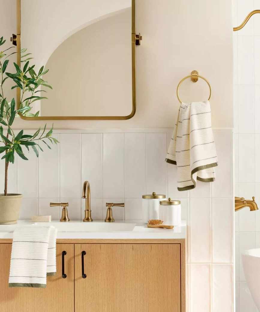 A neutral bathroom with a wooden vanity and brass hardware