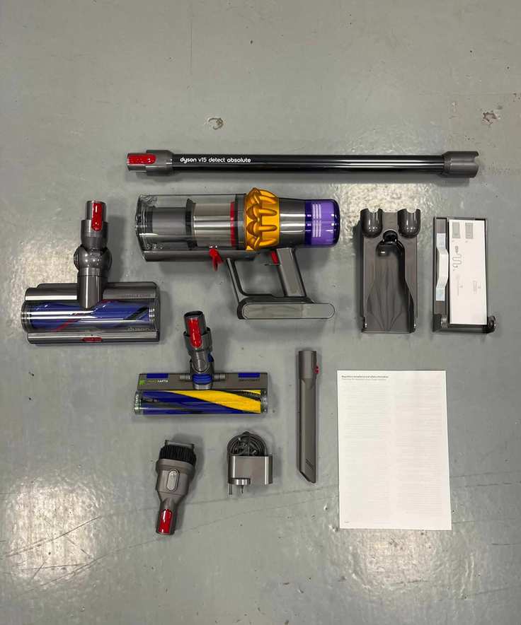All parts and attachment heads of the Dyson V15 Detect Absolute positioned on a gray linoleum floor