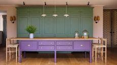 a green and kitchen with a large purple island with oak kitchen steels and a trio of pendant lights above