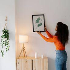Woman placing a framed photo on a wall