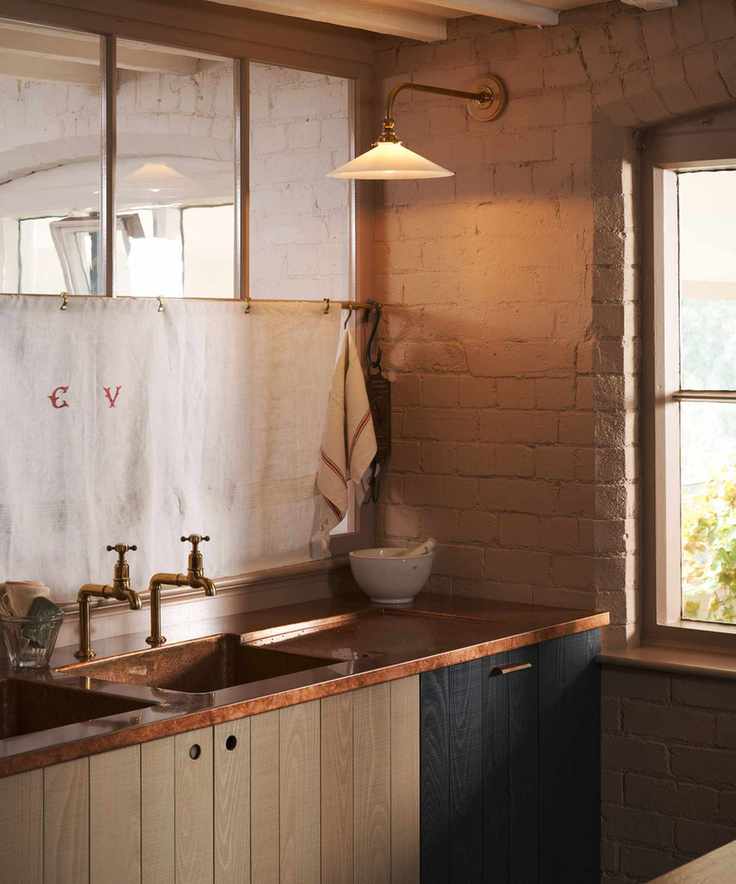 An industrial kitchen with painted wood cabinets, a wood countertop, and a milk shade wall light