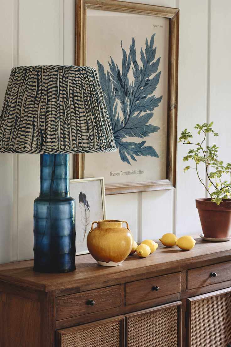 entry way with wood console, table lamp, shiplap walls, artwork, pots