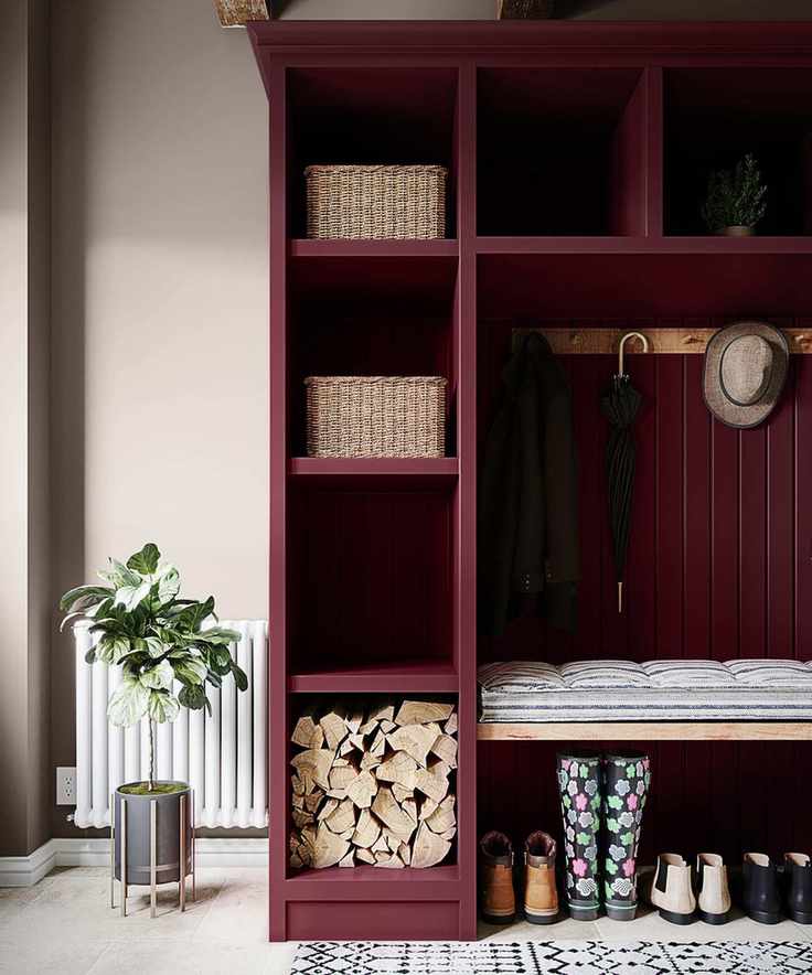 A mudroom with a burgundy colored storage unit with woven storage baskets, a bench, and shoes underneath it