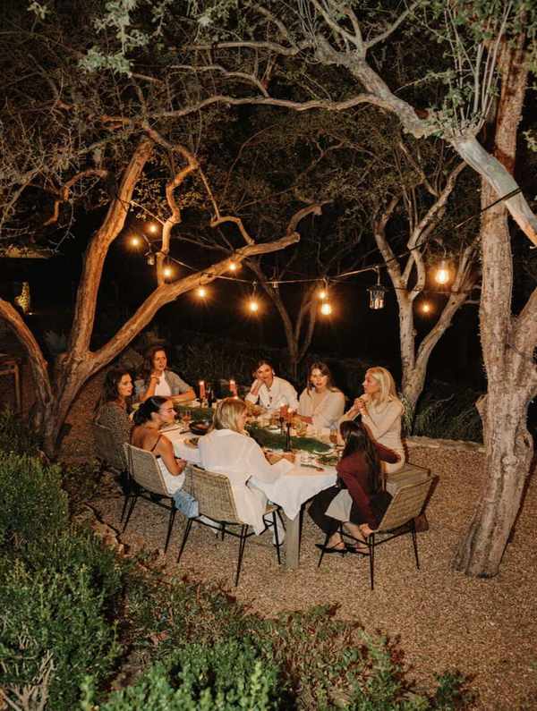 Friends at holiday backyard dinner party around a table at night