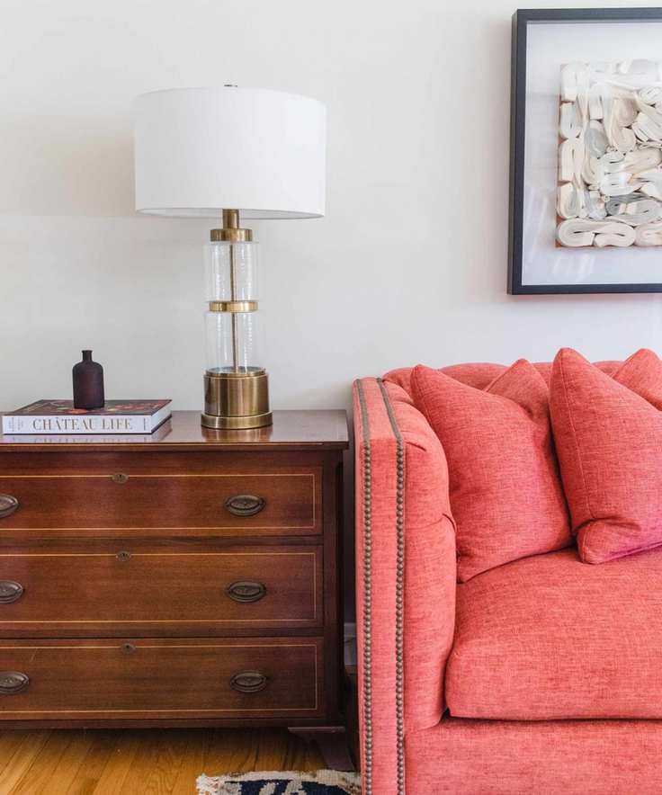 living room with coral sofa and dark wood chest of drawers