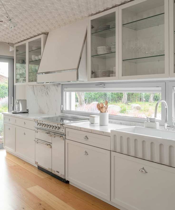 all white kitchen with chrome fixtures and fittings, textured ceiling, cooker hood, marble countertops