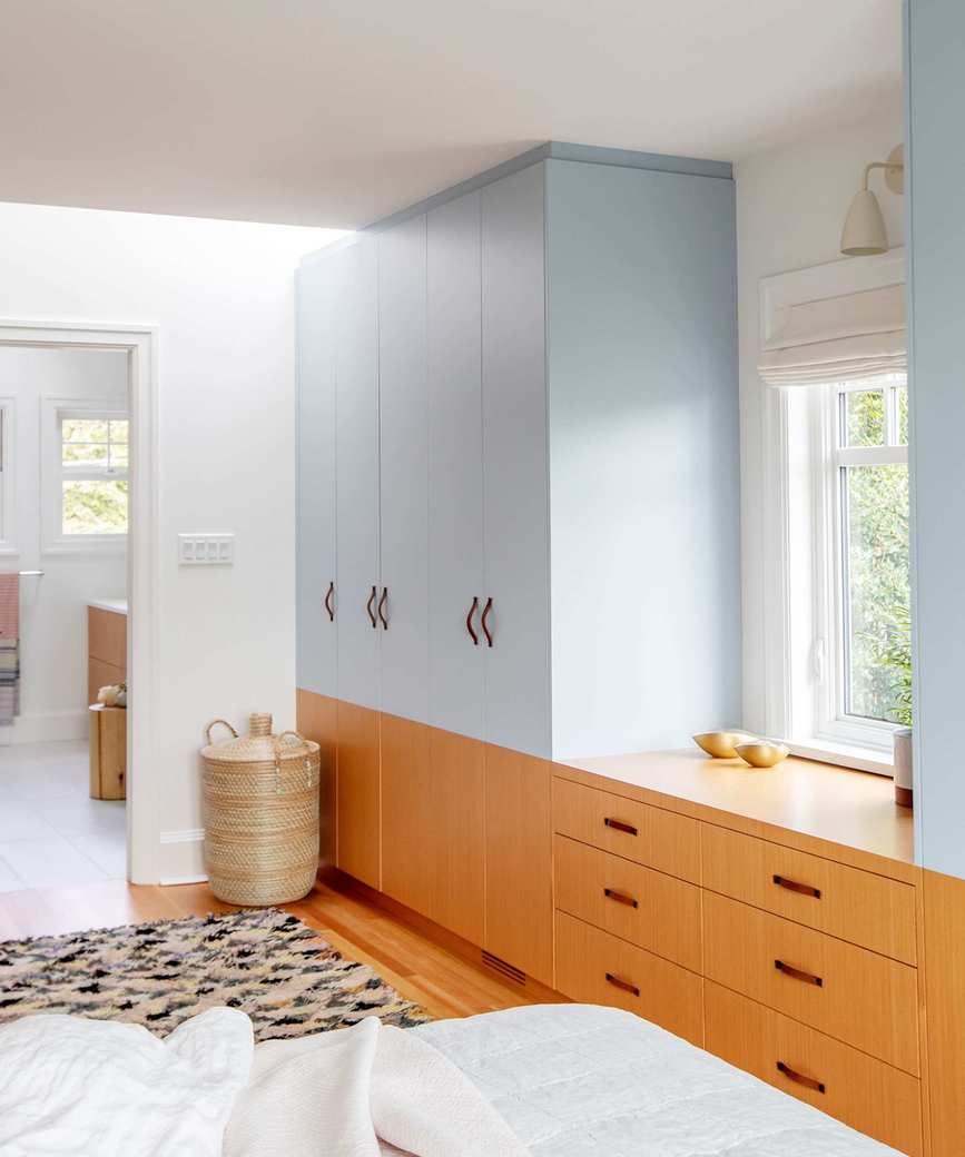 Blue bedroom closets with wooden drawers in bedroom with neutral sheets