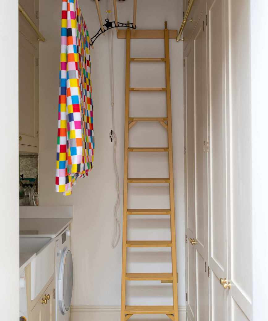 A white utility room with a ladder and colorful patterned towel