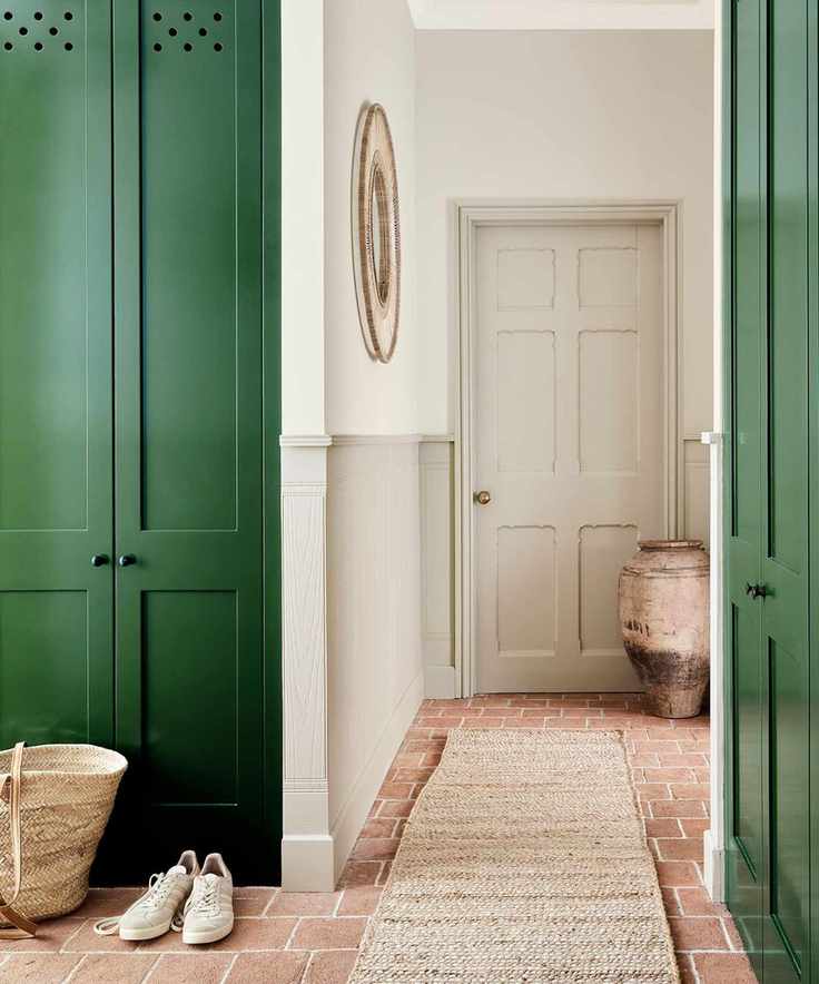Hallway with green-painted cabinets, brick flooring, and a sisal runner leading to the door.
