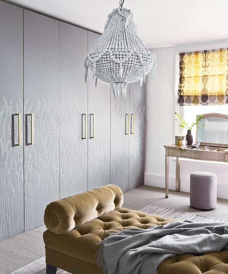 A cozy bedroom with an empire-style chandelier above a velvet daybed
