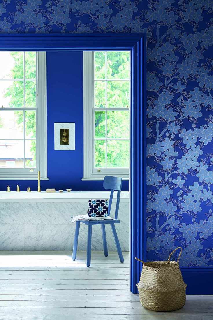 An example of blue bathroom ideas showing a bathroom with blue walls, blue wallpaper and blue woodwork white bath view from a bedroom through to the ensuite