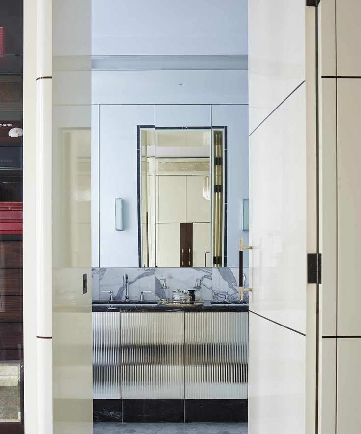 An ensuite bathroom with concealed doors and a large wall mirror above a vanity unit
