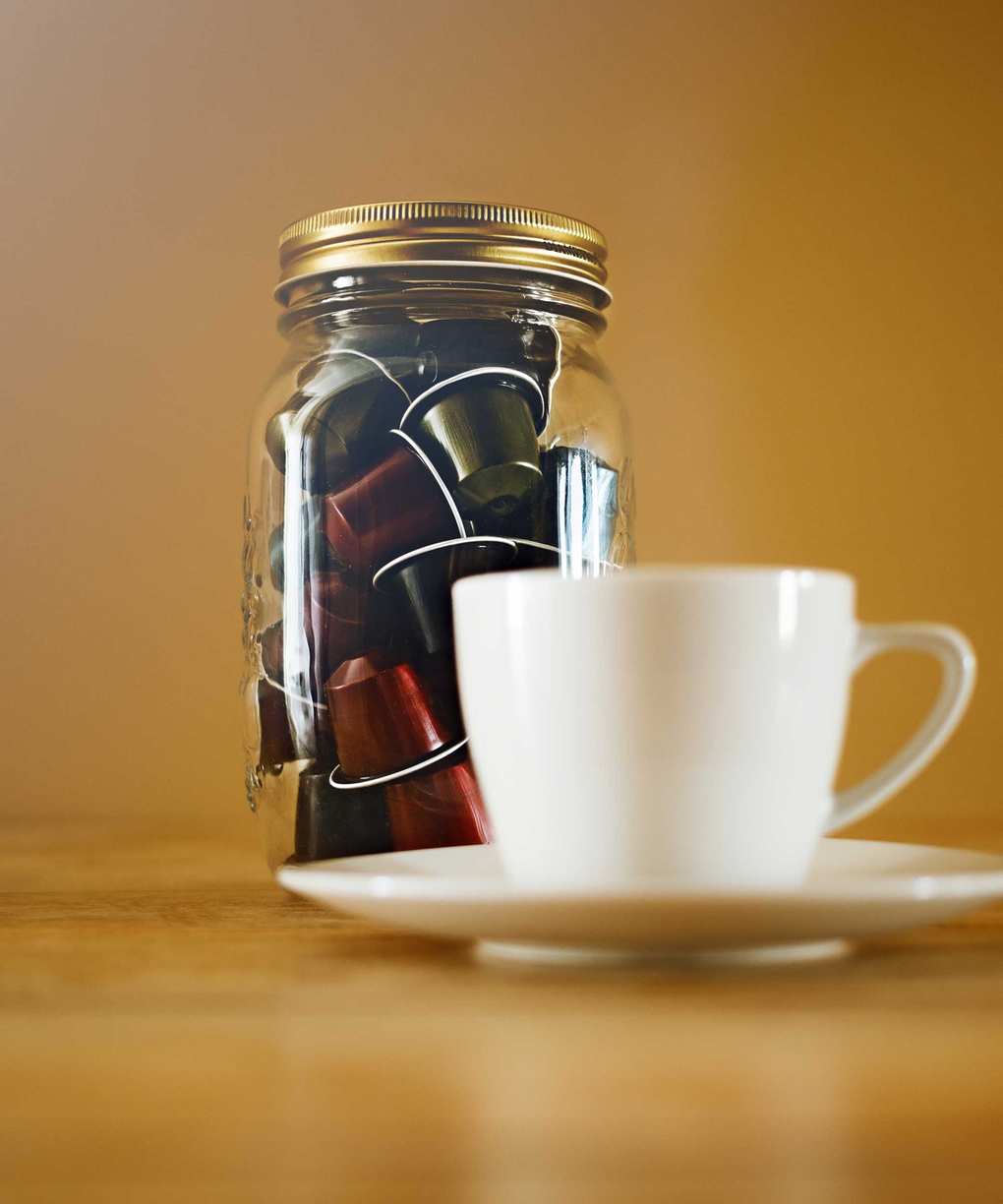 Coffee pods in glass jar with white mug