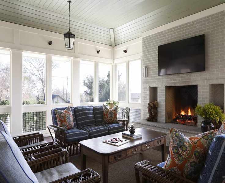 rustic sunroom with walls of windows and brick fireplace at the center