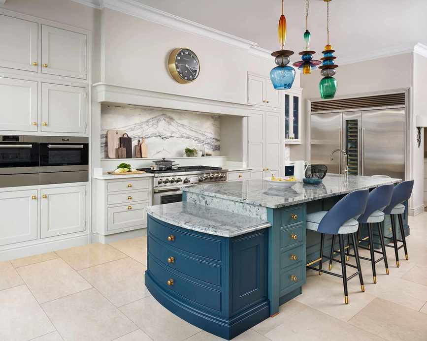 Marble island with blue cabinetry and chairs, in a large neutral scheme