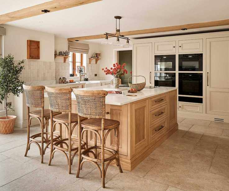 A sociable kitchen with cream cabinets, a wooden island, and tarnished brass hardware throughout