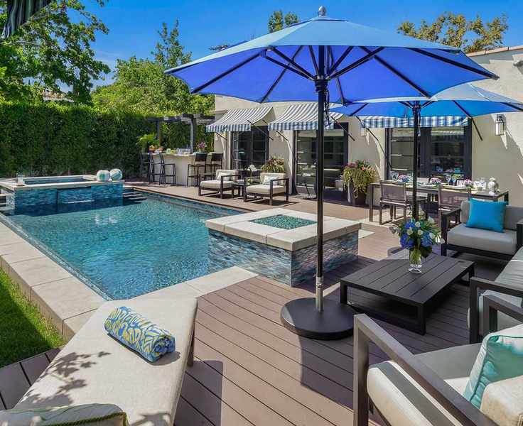 Modern pool area featuring a living room, dining space, and garden bar with umbrellas.