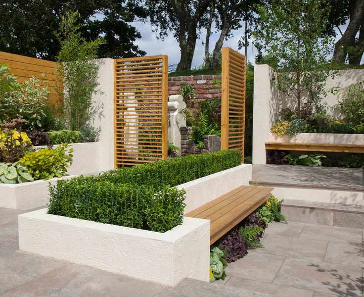 paved courtyard with low hedge in wall with slatted screen and paving