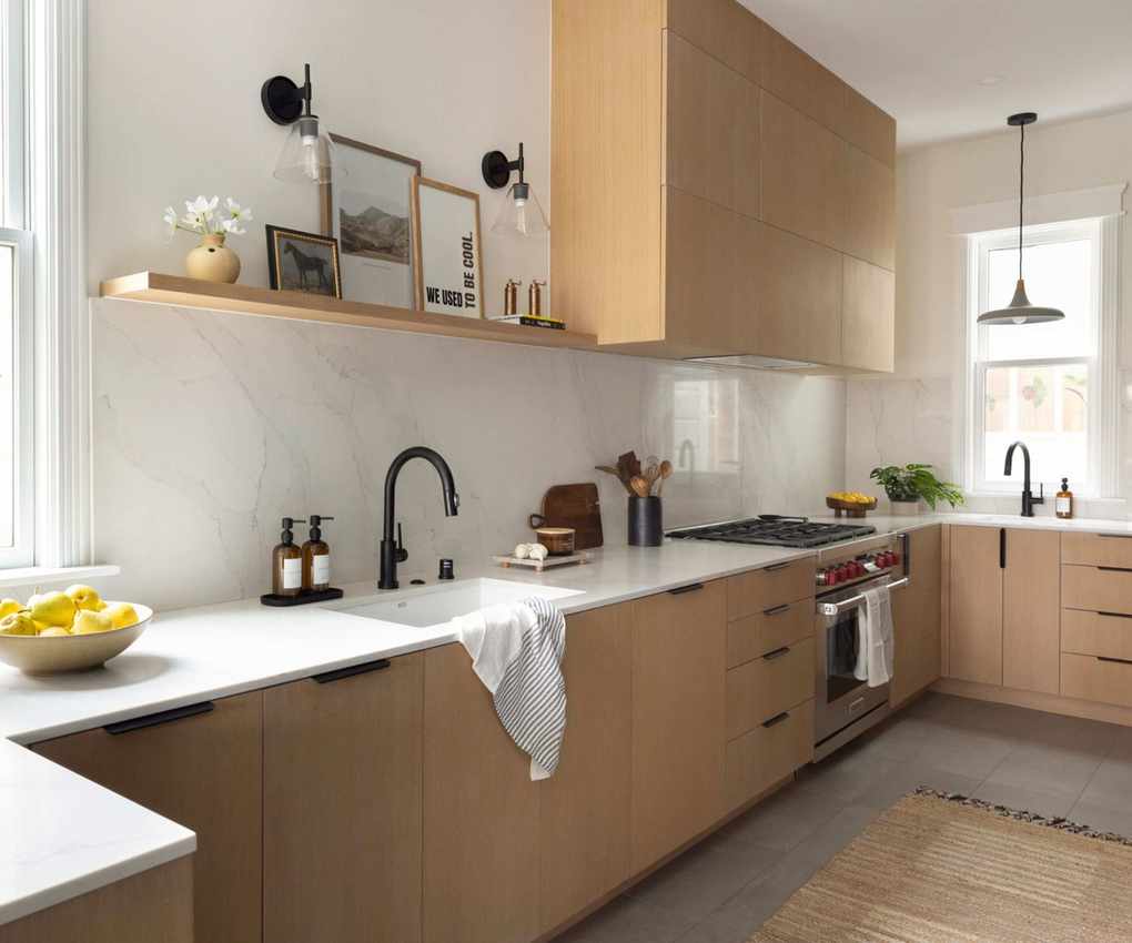 A U-shaped kitchen with wooden cabinets and thin stone countertops