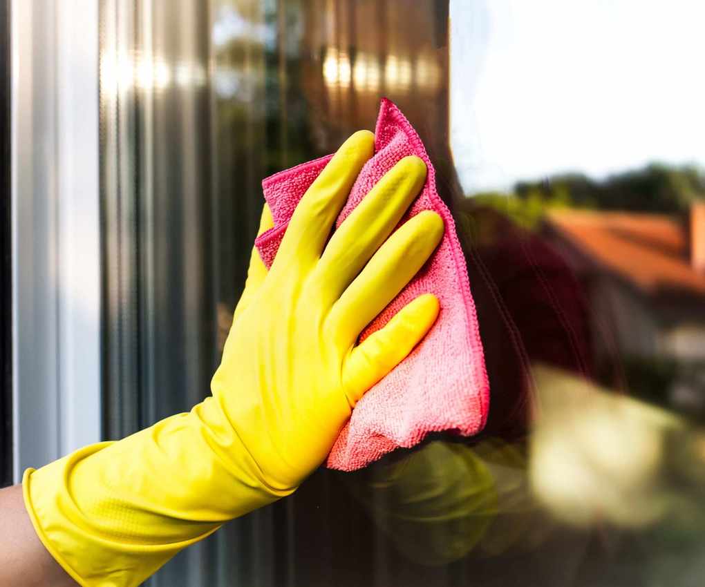Person using a pink cloth to wipe a window