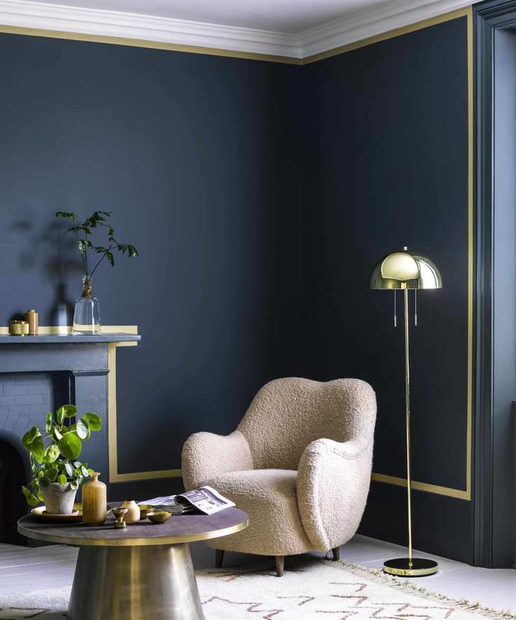 Blue painted living room with yellow accent stripe, cream lounge chair with metallic floor lamp and coffee table