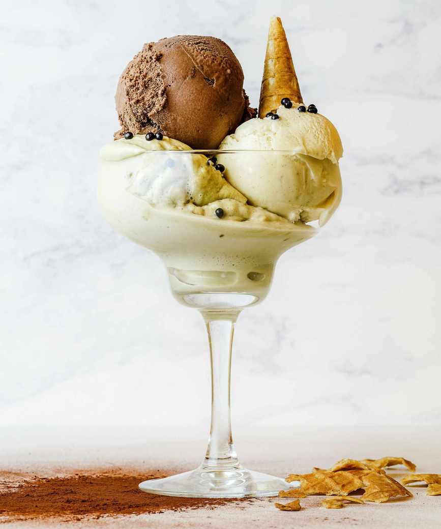 Ice cream sundae with vanilla and chocolate scoops, topped with a small waffle cone