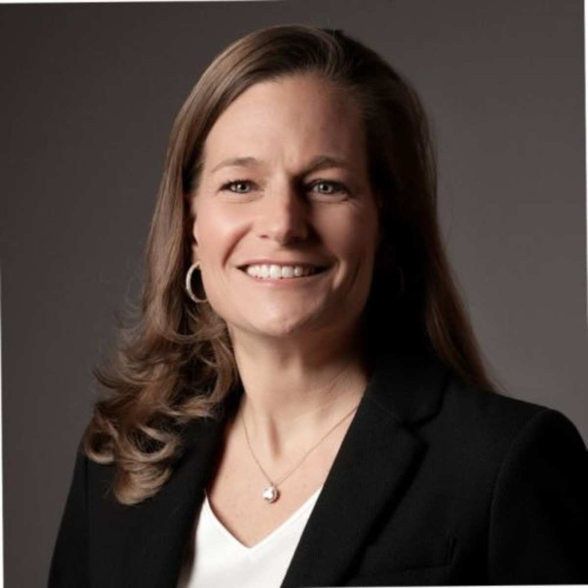 A headshot of Marla Mock smiling, with brown curly hair