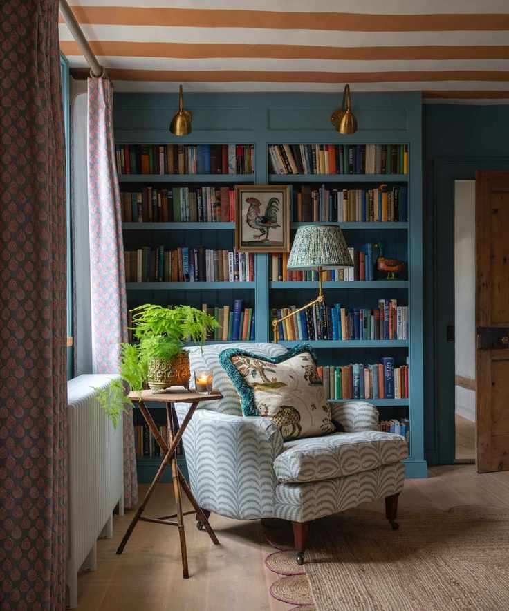 A cozy reading nook with a deep blue bookshelf filled with books and art.