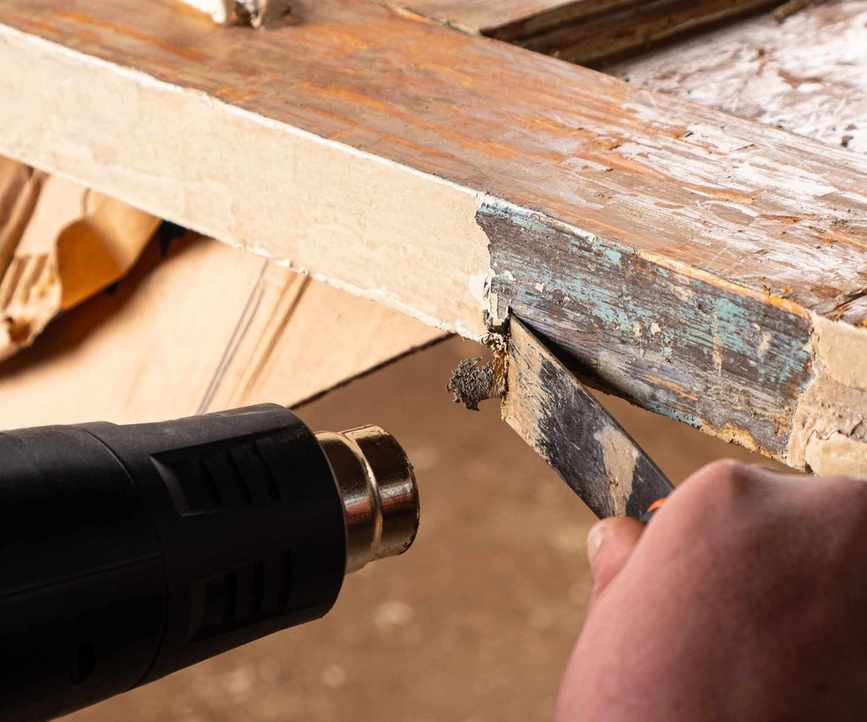Removing old paint from old wooden doors with a spatula and a heat gun, restoring old wooden surfaces