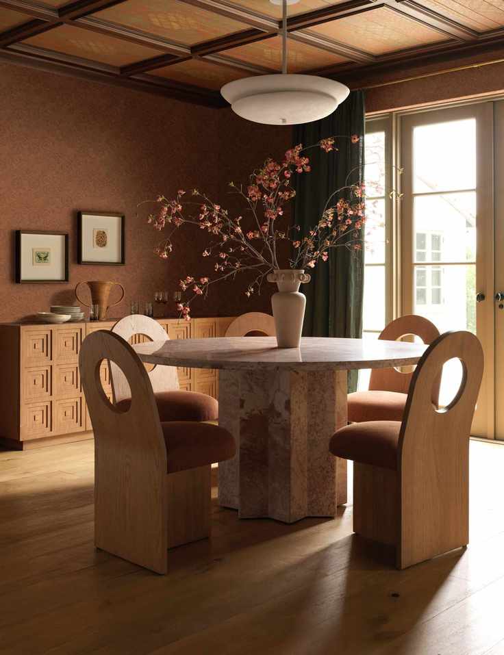 Dining room featuring a pink marble dining room table and five sculptural wooden dining chairs with circular back cutouts