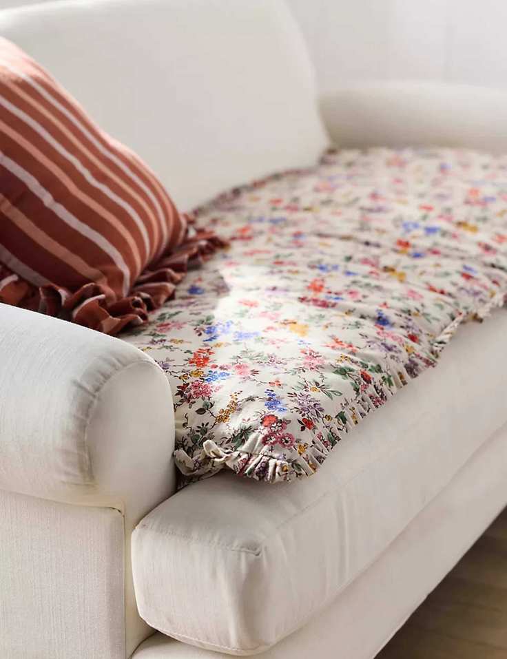 Floral ruffle-bordered sofa topper on a cream sofa with a matching striped throw pillow