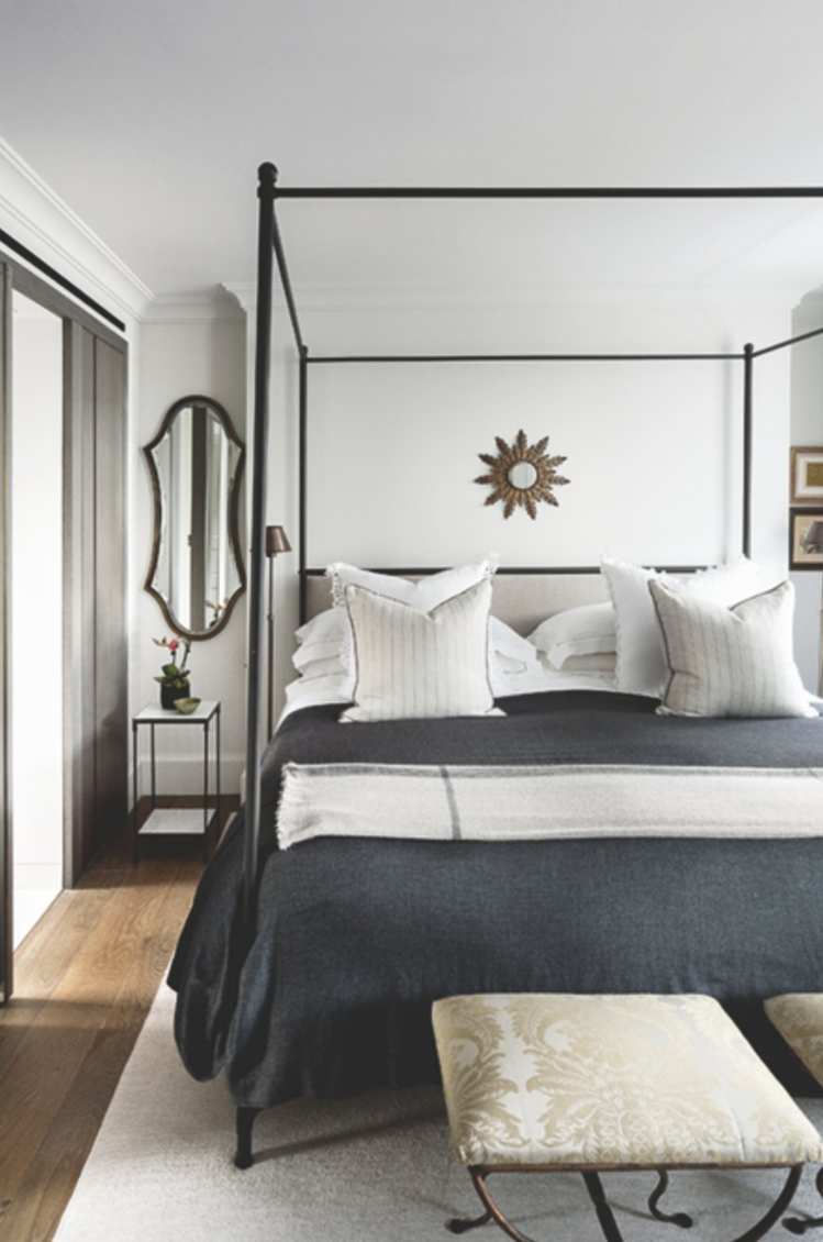 A bedroom with a four poster bed and white walls