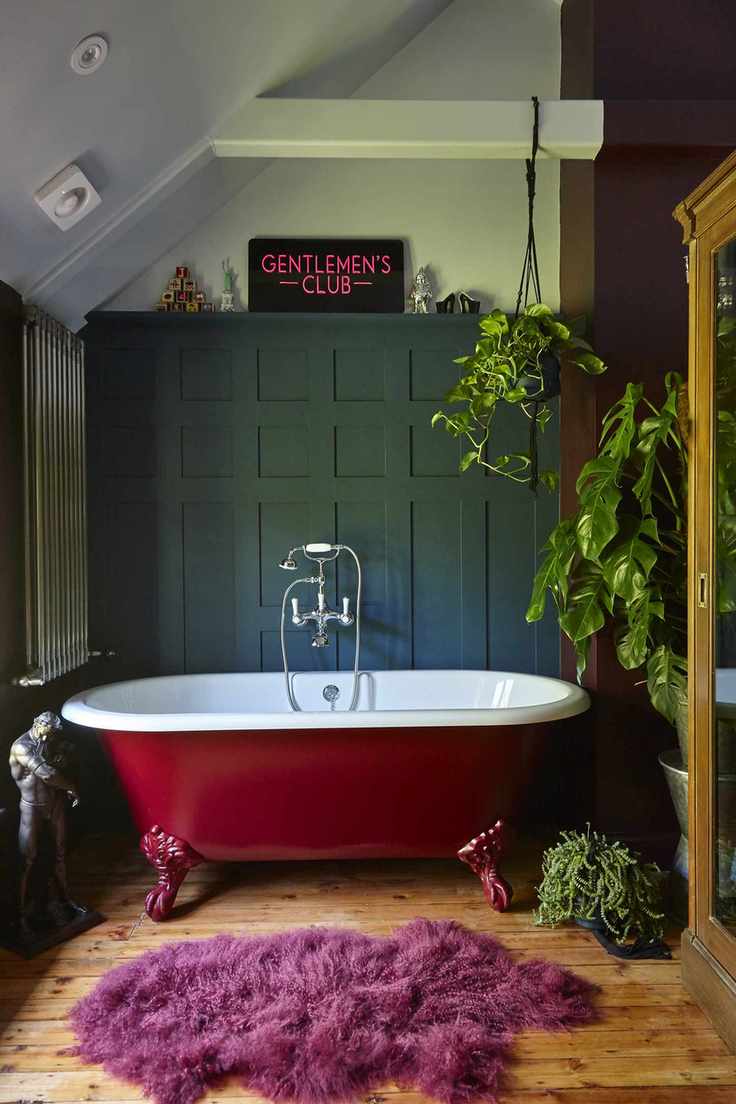 red rolltop bath in green paneled bathroom