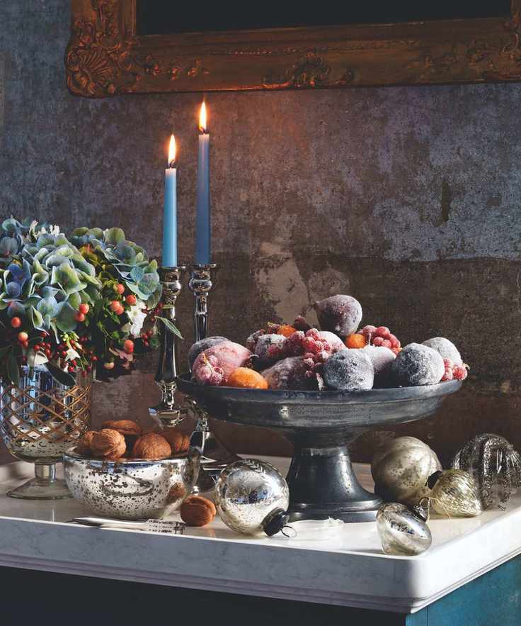 Footed bowl with frosted fruit and blue taper candles