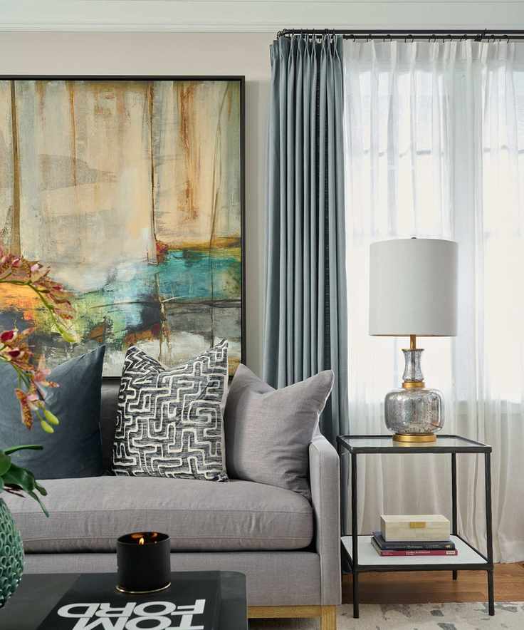 Living room with gray sofa and curatins and large piece of artwork