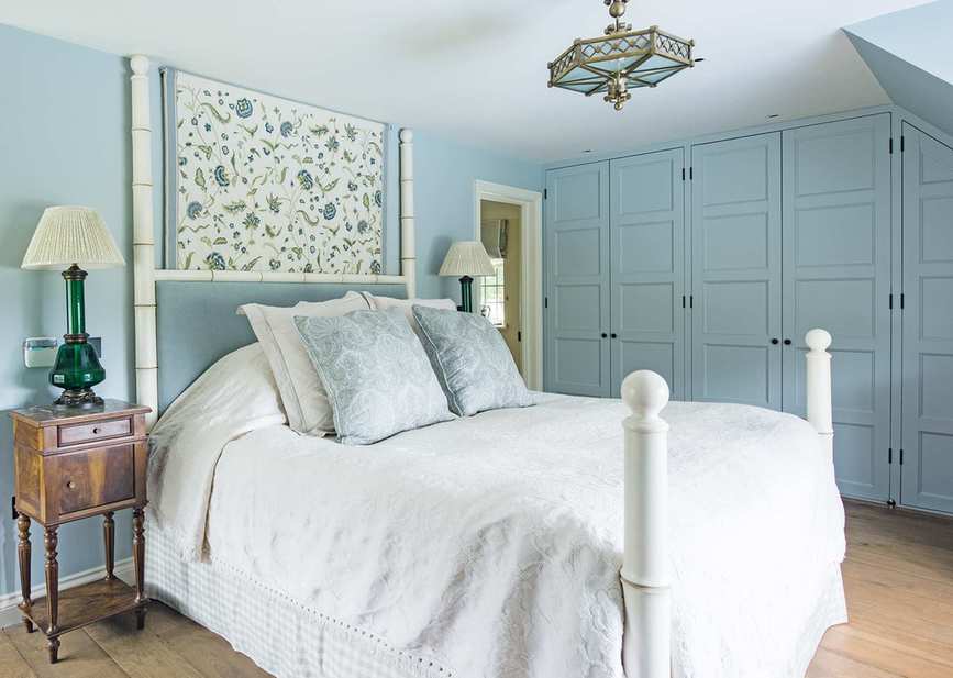 Cottage bedroom showcasing fitted cupboards in a blue attic