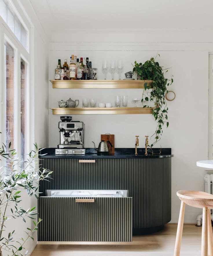 A green coffee station with wooden shelves and a silver coffee machine.