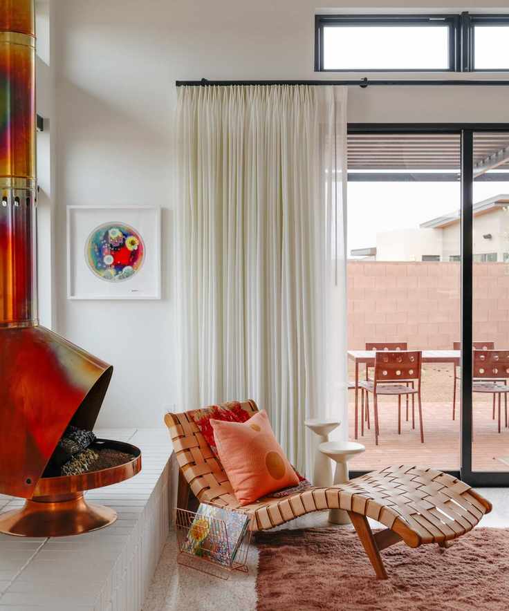 a living room with a hang-down fireplace, a wavy accent chair, a shag carpet, and white walls and curtains