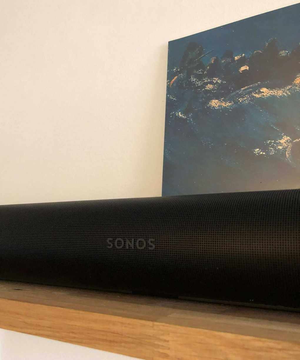 Sonos Arc Ultra soundbar on wooden shelf in front of vinyl sleeve of The Avalanches' Since I Left You and white wall.