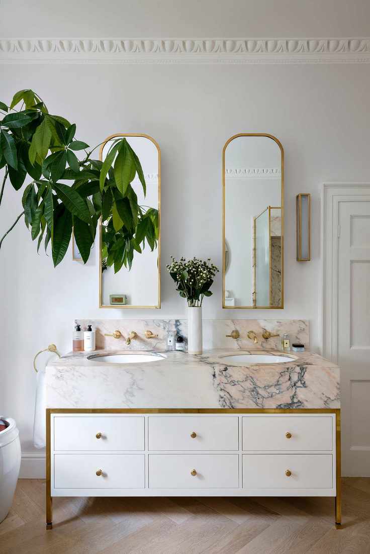 Double sink in a bathroom with a veined marble vanity unit and house plant