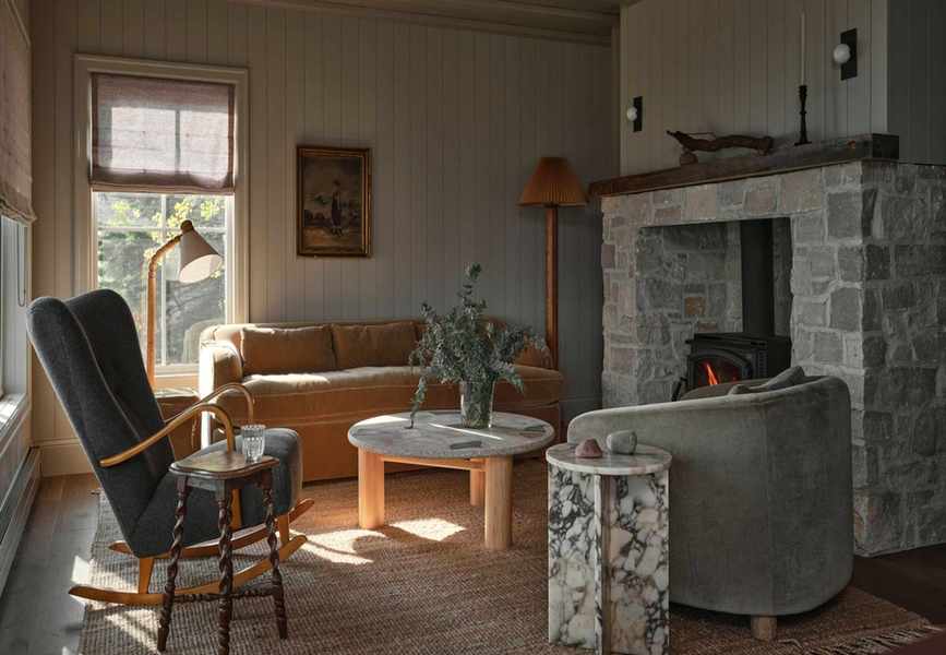 a warm earthy cottage living room with a large stone fireplace and a mix of vintage and modern furniture