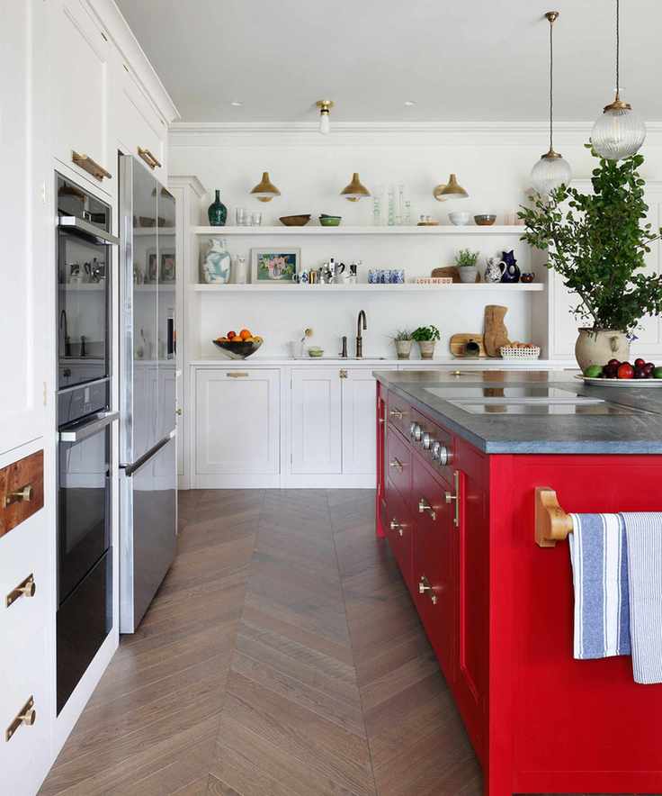 A white kitchen featuring a red island and brass hardware